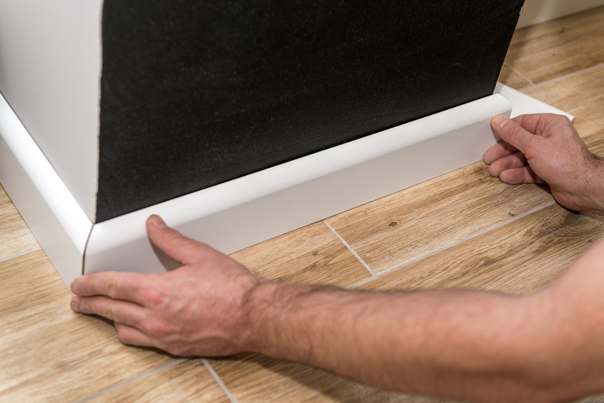 Close up of mans hands installing skirting board
